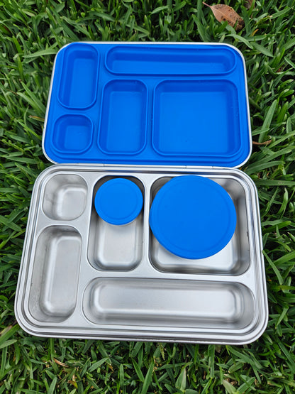 Metal lunch box with blue lids on a grass background